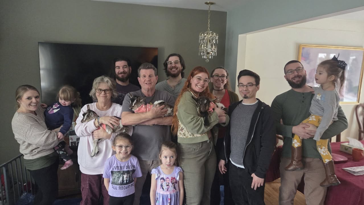 A family together with baby goats during a home visit