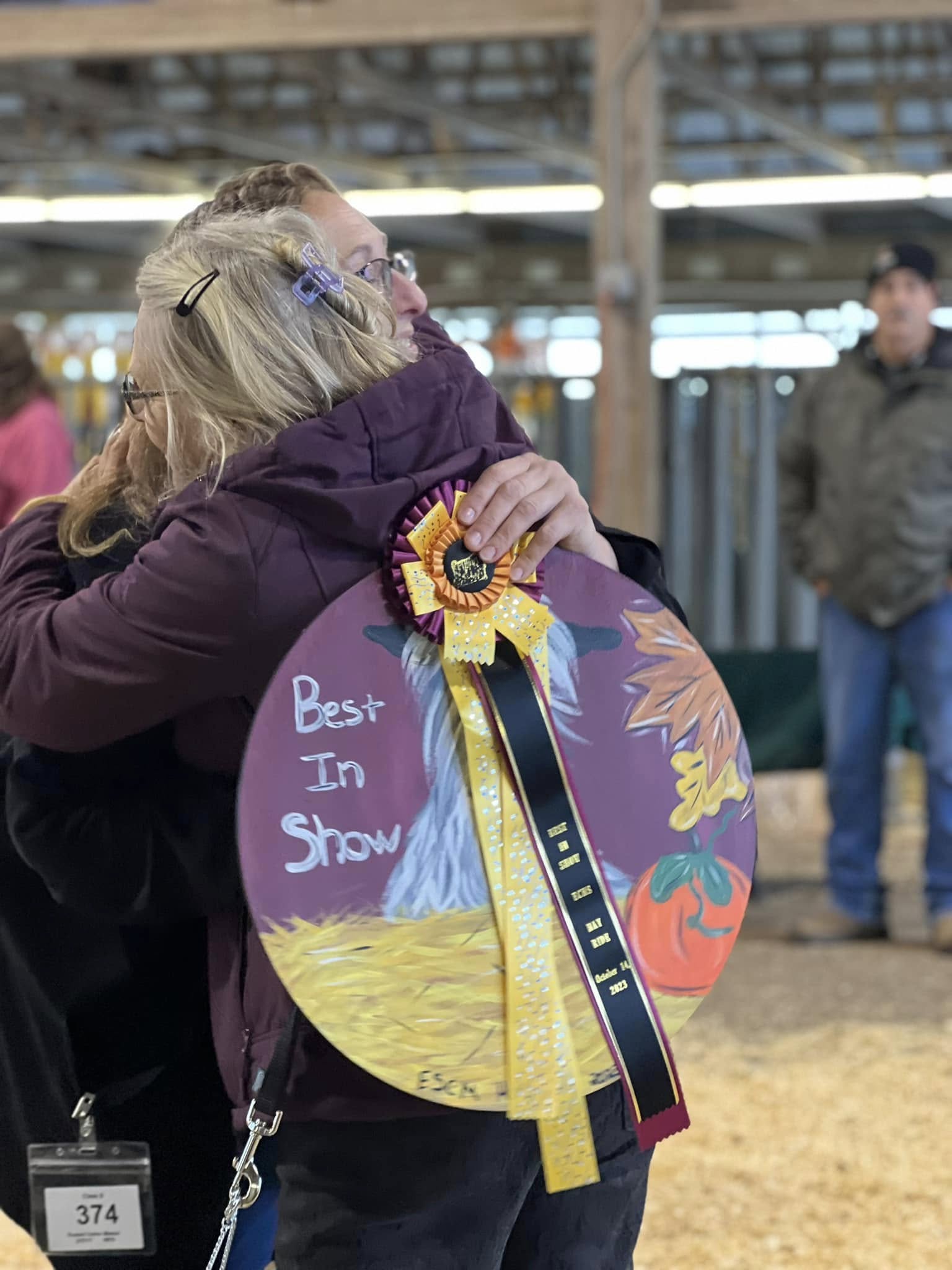 An embrace while holding a Best in Show award at a goat show